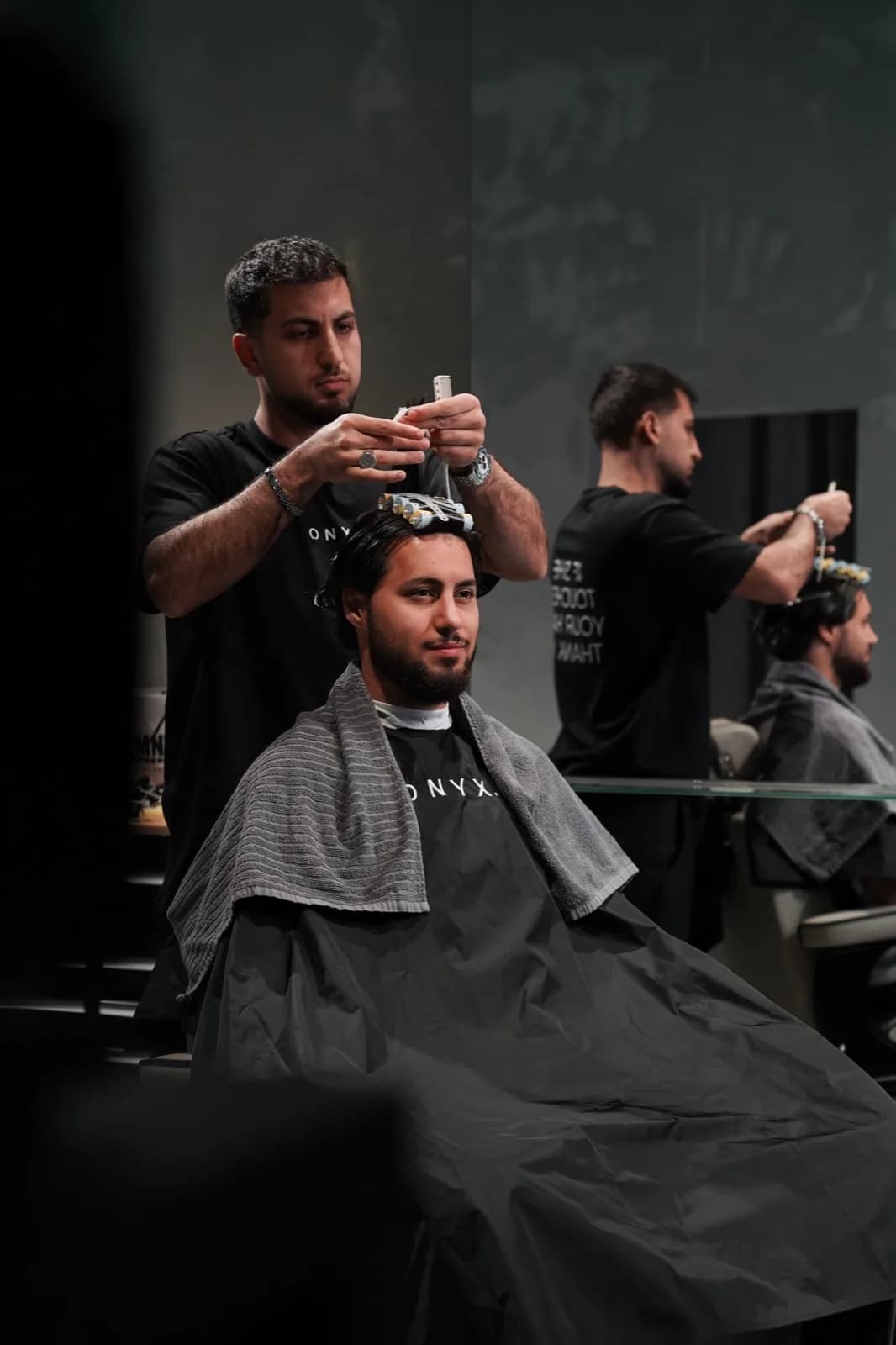 Zwei Barber bei der Arbeit an ihren Stühlen bei ONYX Cuts in Wien